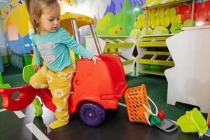 Kids playing at indoor play center playground , girl in toy car. photo