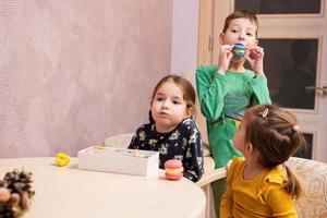 tres niños comen deliciosos y sabrosos macarons de color dulce. foto