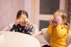 Two sisters put on eyes delicious tasty sweet color macaron. photo