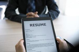 Executives are interviewing and watching the resume via tablet. Focus on resume writing tips, applicant qualifications, interview skills and preparation before the interview. photo