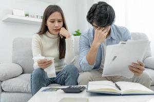 hombre asiático estresado y con dolor de cabeza con grandes facturas o facturas sin dinero para pagar los gastos y la deuda de la tarjeta de crédito. escasez, problemas financieros, hipoteca, préstamo, bancarrota, en quiebra, pobre, billetera vacía foto