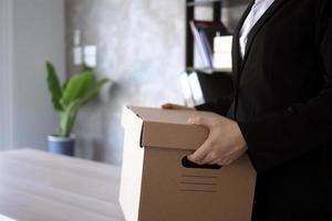 Businesswoman hold boxes for personal belongings and resignation letters. photo