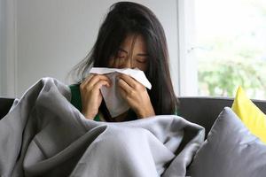 Asian women have high fever and runny nose. Concept of sick people at home photo