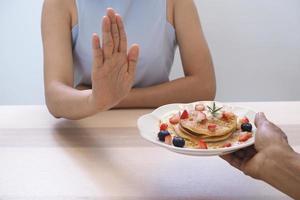 las mujeres empujaban platos de pastelería. deja de comer postre, buena salud foto