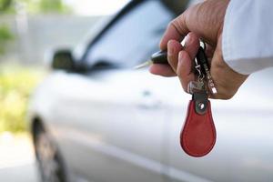The new car owner uses the car key to unlock the door. Buy, sell, rent a car photo