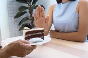 One of the health-care girls used a hand to push a plate of chocolate cake. Refuse to eat foods that contain Trans Fat. photo