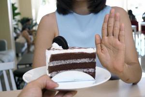 una de las chicas de salud usó una mano para empujar un plato de pastel de chocolate. negarse a comer alimentos que contengan grasas trans. foto