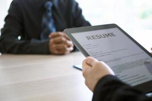 Executives are interviewing and watching the resume via tablet. Focus on resume writing tips, applicant qualifications, interview skills and preparation before the interview. photo