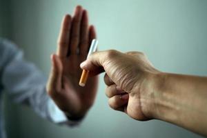 la mano rechazó el cigarrillo que le entregaron. fumar conceptos causas de cáncer de pulmón. solo di no foto