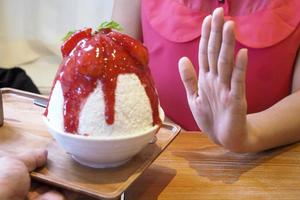 Women push Bingsu cup. Refused to eat all kinds of sweets. Avoid sugar and sweets for good health. diet concept photo