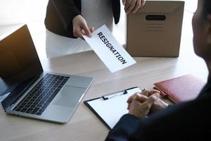 The business woman has a brown cardboard box next to her body and sends a letter of resignation to the executive. Include about resignation, job placement and vacancies. photo