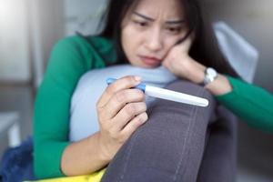 las mujeres asiáticas tienen expresiones faciales ansiosas y piensan en los resultados de las pruebas de embarazo no deseado. foto