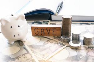 Working desk with yen and coins with note book, income and expense. Saving money concept photo