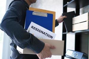 Businessmen are collecting personal items in boxes with resignation letters. Including about resignation from job positions and vacancies photo