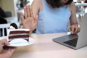 Women refuse to eat cakes while working with computers. Do not eat fussy food during the day for good weight loss. photo