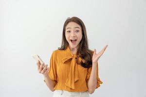 hermosa mujer asiática salió de la expresión de la cara de sorpresa. la mujer se siente sorprendida con el teléfono. sonrisa emocionante y feliz adorable se regocija. muy disfrutar y divertirse relajarse tiempo. guau, chica sosteniendo un teléfono inteligente. foto