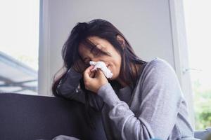 mujer asiática estornudando en tejido. enfermedad, acostado en el sofá foto