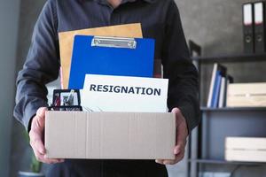 Businessmen are lifting brown paper boxes that collect personal items and resignation letters. The concept of resignation, job positions and vacancies photo