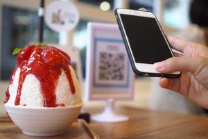 Hands use the phone to scan the QR code to receive discounts from Binsu orders in the cafe.