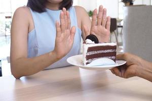 las mujeres solían empujar el plato de la torta con la gente. No comas postres para bajar de peso. foto