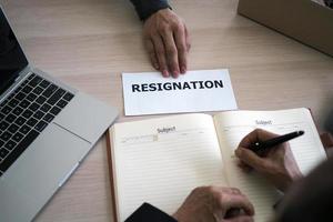 The picture on the top of the desk has a business hand to send a resignation letter to the management. Including about resignation from job positions and vacancies photo