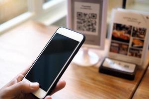 manos usan el teléfono para escanear códigos qr para acumular puntos en restaurantes. foto