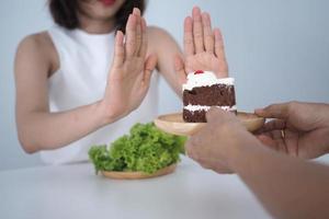 una de las chicas de salud usó una mano para empujar un plato de pastel de chocolate. negarse a comer alimentos que contengan grasas trans. foto