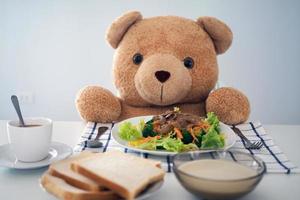 Teddy bear eating breakfast at the table in the house photo