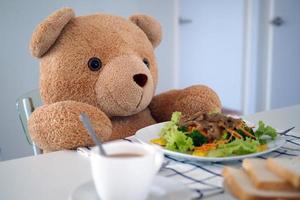 oso de peluche desayunando en la mesa de la casa foto