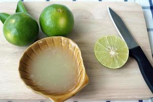 Fresh squeezed lemon juice is put in the cup. With cutlery and lime cut photo