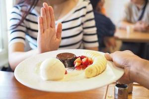 las mujeres empujaban el plato de postre con la gente. No comas postres para bajar de peso. foto