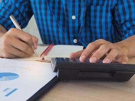 Employees use a calculator to calculate statistics about their work and write down their data into the notebook. Working concept. photo