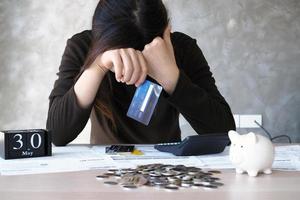 una mujer joven con una deuda de tarjeta de crédito y muchas facturas colocadas sobre la mesa. foto