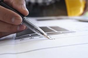 The chief engineer hands the pen to check the blueprint of the building and interior decoration project. photo