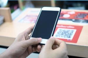 Hands use the phone to scan the QR code to receive discounts on purchases in the department store. photo