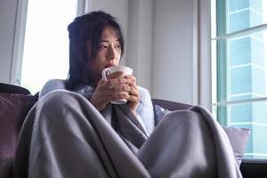 Asian woman is sick having stuffy nose, flowing water in the hands, wiping paper, high fever Sitting on the sofa inside the house photo