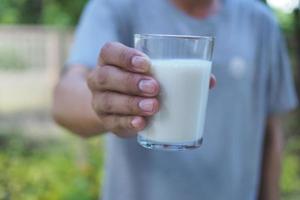 hombre sosteniendo un vaso de leche. invita a todos a tomar leche todos los días para fortalecer con calcio. foto