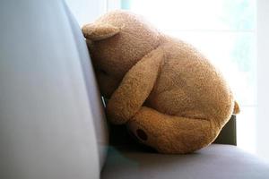 el concepto de duelo de los niños. el oso de peluche se sienta en el sofá dentro de la casa, solo, luciendo triste y decepcionado. foto