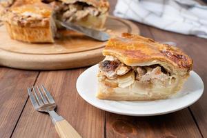 Homemade meat pie with greenery on wooden background photo