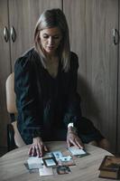 una mujer joven y hermosa en su oficina sobre la mesa presenta cartas de tarot metafóricas, adivinación, buscando una respuesta a una pregunta foto