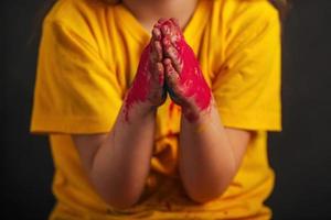 primer plano de las manos de los niños en colores holi coloridos doblados en oración, las manos de los niños piden ayuda. festival indio de colores holi. foto