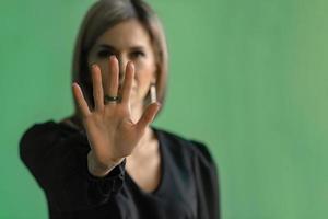 Girl, young woman in dark clothes shows palm, hand forward, stop sign and no. Hand signs, the ability to say no. selective focus photo