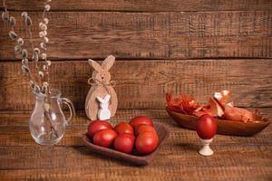 on a wooden background Easter eggs, painted with natural vegetable dyes, onion peel, next to a wooden Easter Bunny and willow photo