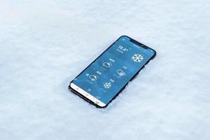teléfono en la nieve con una aplicación meteorológica. temperatura en farenheit con pronostico para varios dias foto