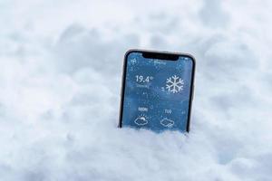 el teléfono en la nieve con un pronóstico del tiempo muestra la temperatura en Fahrenheit foto