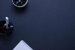 Minimalist and organized work desk featuring a plant, pens, and a notepad with copy space on desk surface photo