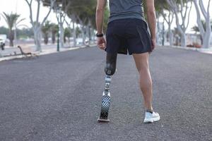 Crop runner with artificial blade leg standing on asphalt road photo