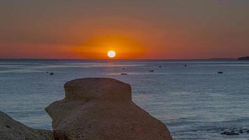 Zeitraffer eines Sonnenuntergangs mit Nahaufnahme des Sonnenballs über dem Meer unter klarem Himmel video