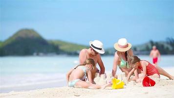 Familie macht Sandburg am weißen Strand in den Sommerferien video