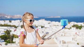 adorable niña tomando selfie foto de fondo ciudad de mykonos en grecia video